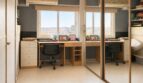 Helles Arbeitszimmer im Penthouse Palma mit Schreibtisch, Spiegelschrank und Stadtblick aus dem Fenster.