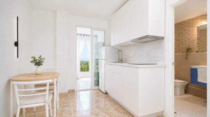 Helle Küche mit weißen Einbauschränken, kleinem Esstisch und Balkonzugang im Penthouse Palma de Mallorca