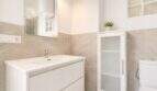Modernes Badezimmer des Penthouse in Palma mit weißem Waschtisch, Spiegelschrank und elegantem Fliesendekor.