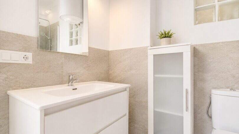 Modernes Badezimmer des Penthouse in Palma mit weißem Waschtisch, Spiegelschrank und elegantem Fliesendekor.