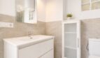 Modernes Badezimmer im Penthouse Palma: weißer Waschtisch, Spiegelschrank und Natursteinwandfliesen.