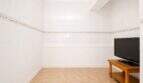 Weißgefliestes Zimmer im Penthouse Palma mit Holz-TV-Möbel, LG-Fernseher und dekorativem Fliesenfries.