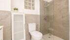 Modernes Badezimmer im Penthouse Palma mit Dusche, WC und eleganten Natursteinfliesen in Beige-Grau.