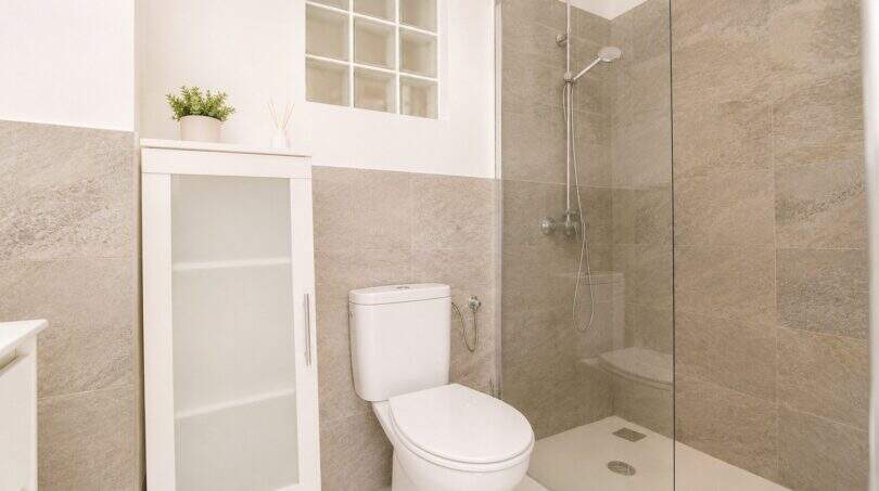 Modernes Badezimmer im Penthouse Palma mit Dusche, WC und eleganten Natursteinf­liesen in Beige-Grau.