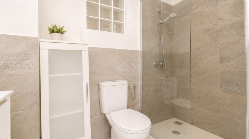 Modernes Badezimmer des Penthouses mit Glasdusche, WC und Natursteinoptik-Fliesen in Palma de Mallorca.