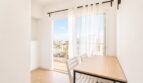 Heller Essbereich mit Holztisch, weißen Stühlen und Balkonzugang mit Meerblick im Penthouse Palma de Mallorca