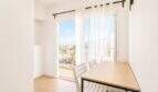 Helles Esszimmer im Penthouse Palma de Mallorca mit Holztisch, weißen Stühlen und Balkon mit Meerblick.