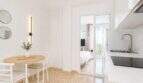 Helles Penthouse in Palma: offene Küche mit Marmor-Arbeitsplatte, Essbereich und Blick ins Schlafzimmer.