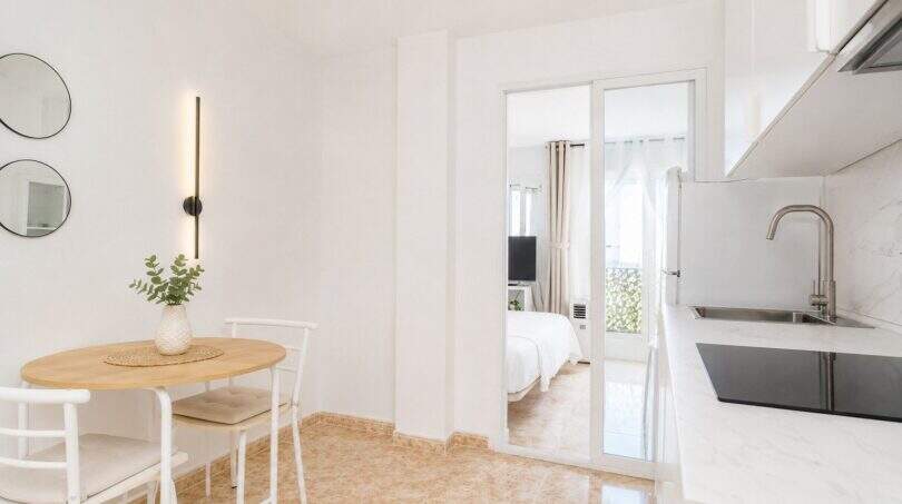 Helles Penthouse in Palma: offene Küche mit Marmor-Arbeitsplatte, Essbereich und Blick ins Schlafzimmer.
