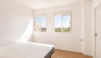 Helles Schlafzimmer im Penthouse Palma de Mallorca mit zwei Fenstern, Stadtblick und weißen Wänden