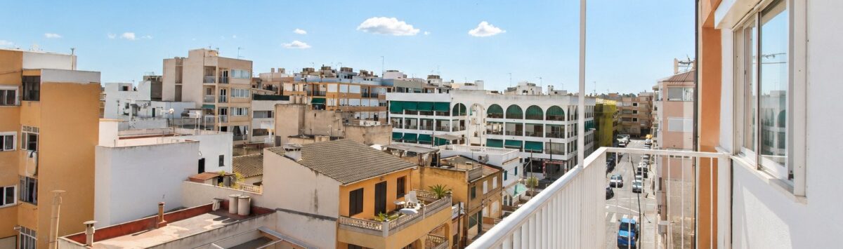 Sonniger Balkon eines Penthouses in Palma de Mallorca mit Stadtpanorama und blauem Himmel.