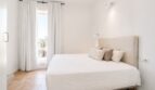 Helles Schlafzimmer im Penthouse Palma mit Doppelbett, weißen Wänden und Fenster mit Palmenblick