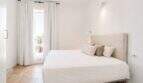 Helles Schlafzimmer im Penthouse Palma de Mallorca mit Doppelbett, weißen Wänden und Fenster mit Palmenblick.
