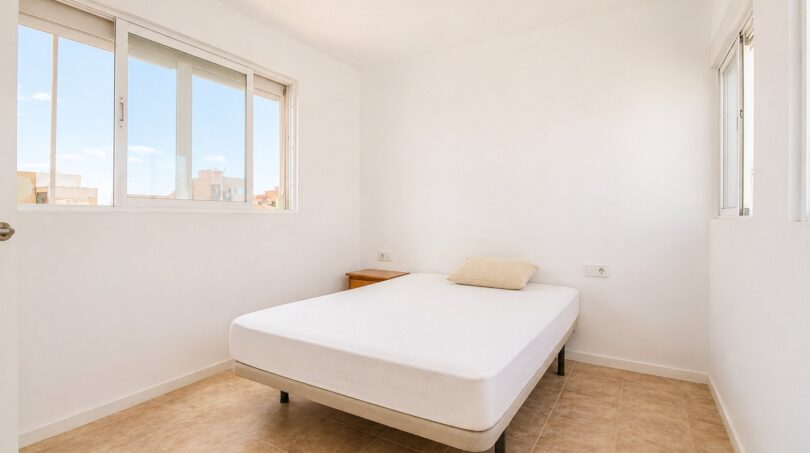 Helles Schlafzimmer im Penthouse Palma de Mallorca mit Doppelbett, weißen Wänden und Fliesenboden