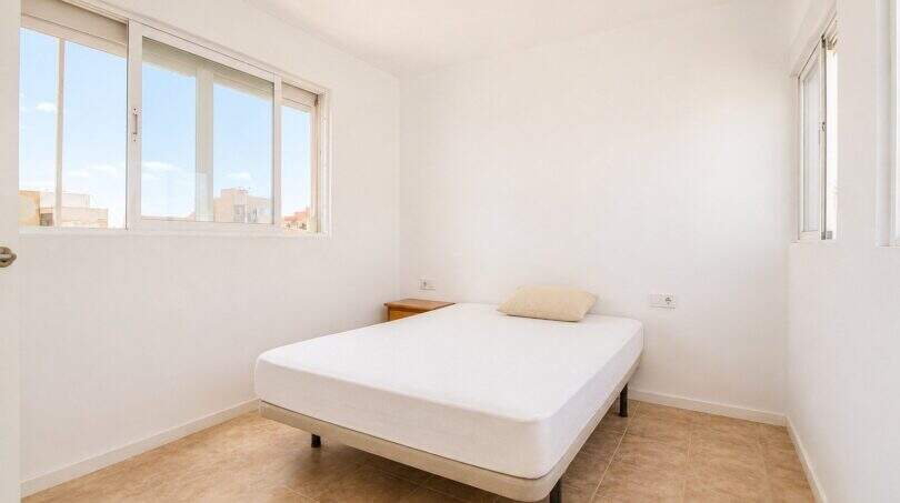 Helles Schlafzimmer im Penthouse Palma de Mallorca mit Doppelbett, weißen Wänden und großen Fenstern.