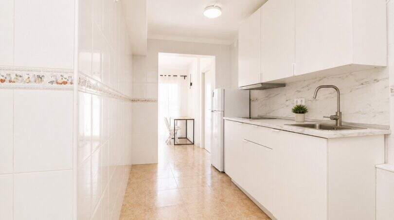 Helle Küche mit weißen Schränken, Marmoroptik-Rückwand und modernem Waschbecken im Penthouse Palma de Mallorca