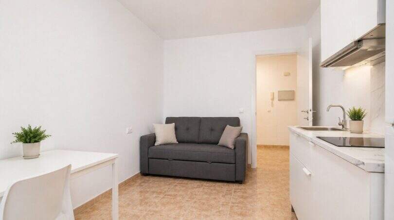 Helles Studio-Apartment mit grauem Sofa, weißer Küchenzeile und Esstisch im Penthouse Palma de Mallorca