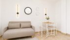 Helles Wohnzimmer des Penthouses mit beigem Sofa, kleinem Esstisch und modernen Wandleuchten