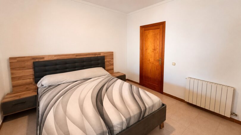 Schlafzimmer der Finca Sencelles mit Doppelbett, Holzkopfteil, Heizkörper und Holztür