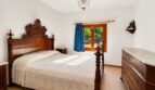Schlafzimmer der Finca Sencelles mit antikem Holzbett, Kommode und Fenster zum Garten