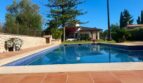 Finca Sencelles: Großer blauer Pool mit Terrakottaboden, Steinmauer und mediterrane Villa im Hintergrund.