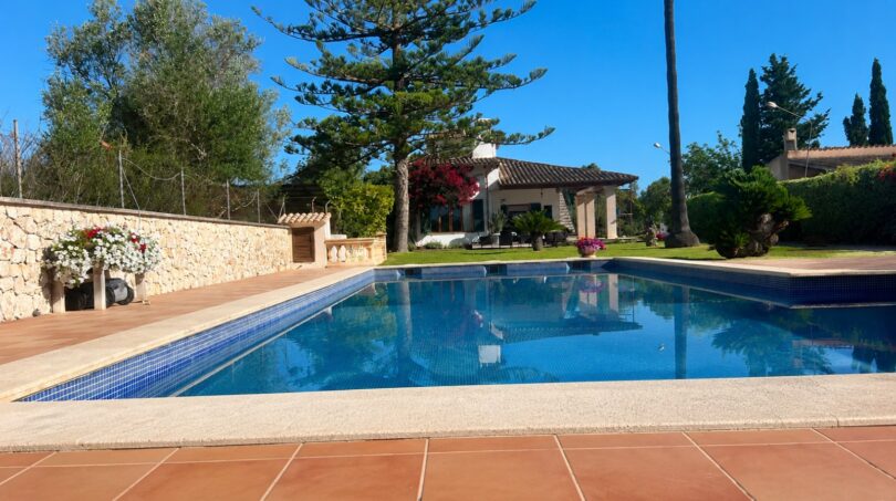 Finca Sencelles: Großer blauer Pool mit Terrakottaboden, Steinmauer und mediterrane Villa im Hintergrund.