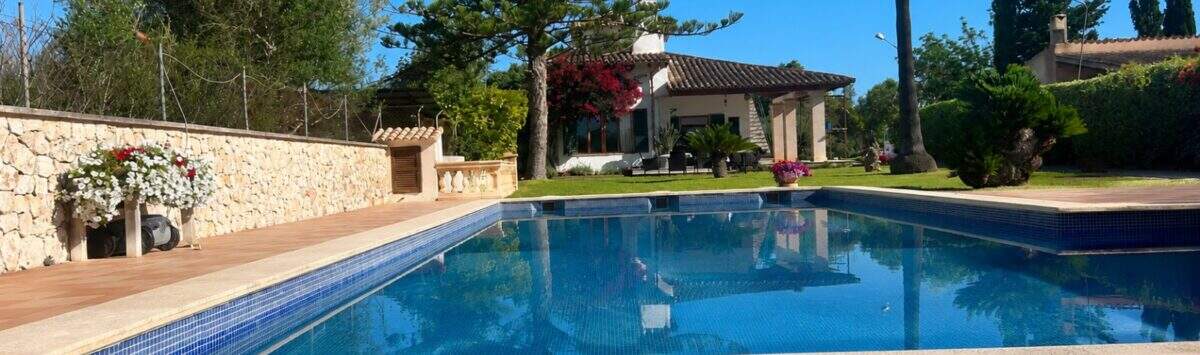 Finca Sencelles: Großer blauer Pool mit Terrakottaboden, Natursteinmauer und mediterranem Landhaus im Hintergrund.