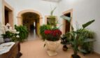 Eleganter Eingangsbereich der Finca mit Rundbogenarchitektur, Natursteinrahmen und üppigen Topfpflanzen.