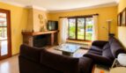 Wohnzimmer der Finca mit Kamin, dunklen Sofas und Blick auf Pool und Garten