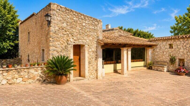 Rustikale Naturstein-Finca bei Sencelles mit überdachter Terrasse, Innenhof und mediterraner Bepflanzung.