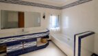 Badezimmer der Finca mit blau-weißen Azulejo-Fliesen, Einbaubadewanne und großem Wandspiegel über dem Waschtisch.