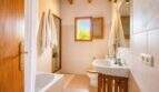 Helles Badezimmer der Finca mit Holzbalkendecke, Badewanne, WC und Waschbecken in Lloret de Vistalegre.