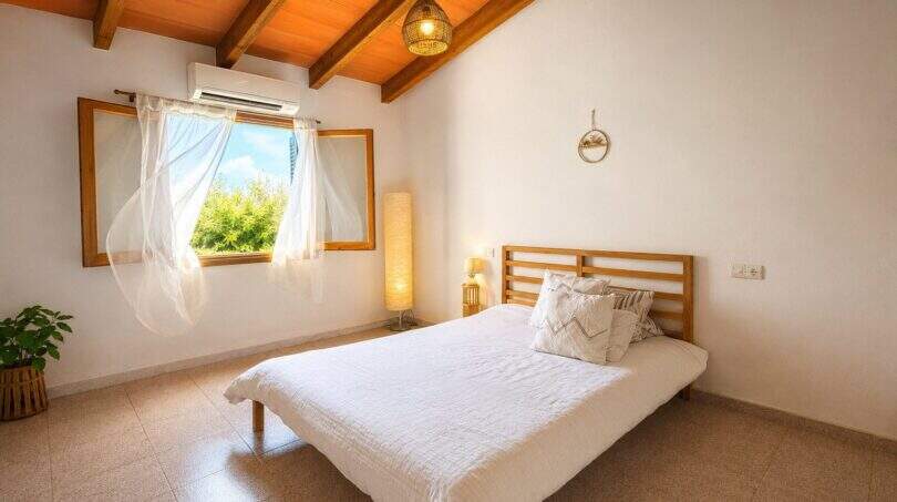 Helles Schlafzimmer der Finca in Lloret de Vistalegre mit Holzbalkendecke, Doppelbett und Klimaanlage