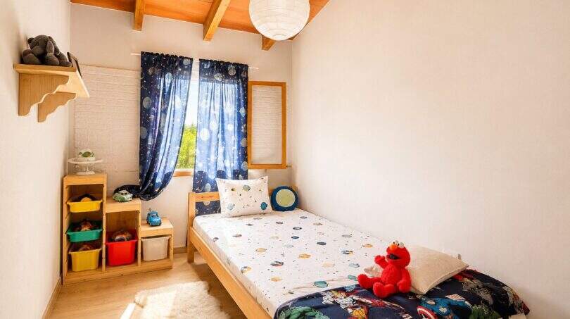 Kinderzimmer der Finca mit Holzbalkendecke, Weltraum-Deko, Elmo-Plüschtier und buntem Spielzeugrega