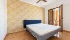Bedroom with double bed, blue headboard, yellow floral wallpaper accent and ceiling fan in Palma-Camp Redó