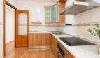 Bright kitchen with wooden fronts, glass ceramic hob, stainless steel hood and tiled walls in apartment in Palma-Camp Redó