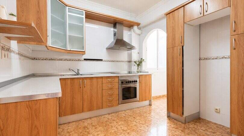 Bright kitchen with wooden fronts, built-in oven, range hood and arched window in apartment in Palma-Camp Redó
