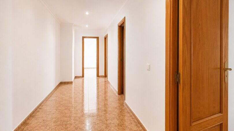 Bright hallway of the apartment in Palma with marble floor, white walls and wooden doors