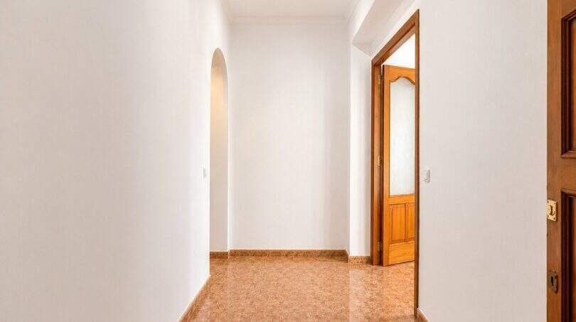 Bright hallway of the apartment in Palma with arched niche, terracotta tiles and wooden doors