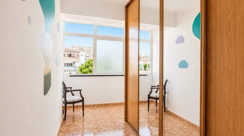 Bright children's room with built-in wardrobe, mirror door, colorful wall stickers and view of Palma-Camp Redó