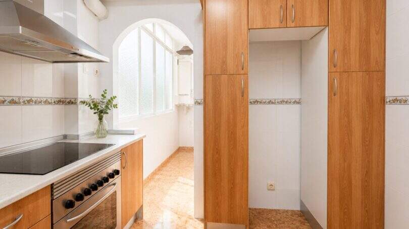 Bright kitchen with wooden fronts, ceramic hob, oven, extractor hood and large pantry in Palma