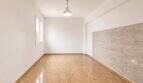 Empty living room with stone wall cladding, terracotta floor and pendant light in apartment in Palma-Camp Redó