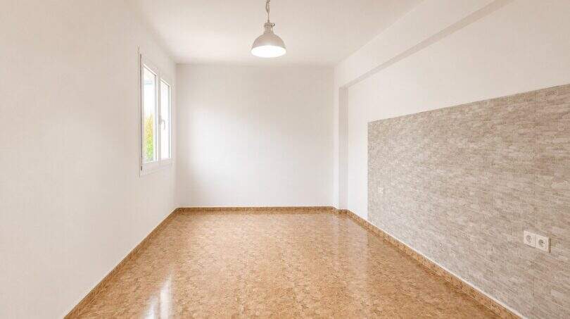 Empty living room with stone wall cladding, terracotta floor and pendant light in apartment in Palma-Camp Redó