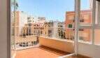 Bright balcony with tiled floor and white railing, view of sunny city buildings in Palma de Mallorca