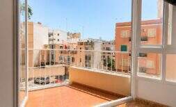 Heller Balkon mit Fliesenboden und weißem Geländer, Blick auf sonnige Stadtgebäude in Palma de Mallorca