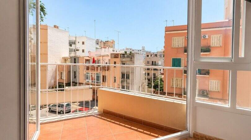 Bright balcony with tiled floor and white railing, view of sunny city buildings in Palma de Mallorca
