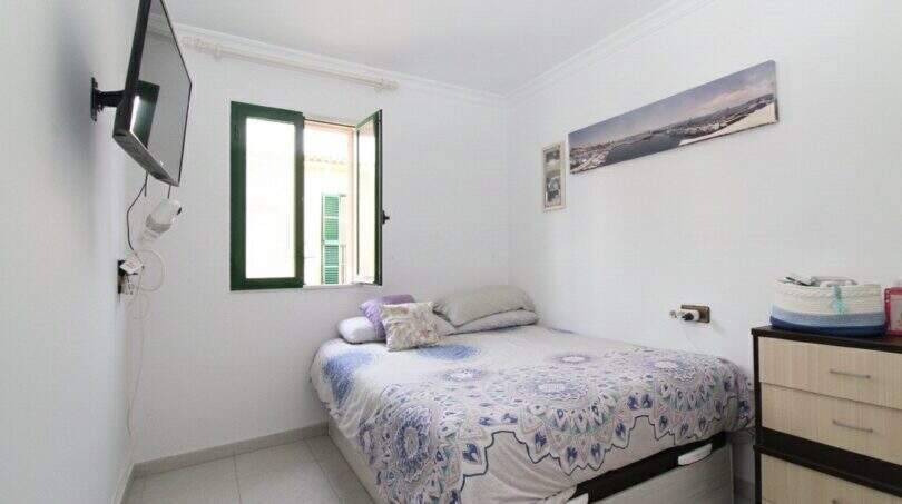 Helles Schlafzimmer im Stadthaus Portixol mit Doppelbett, Wandmontage-TV und grünem Fenster