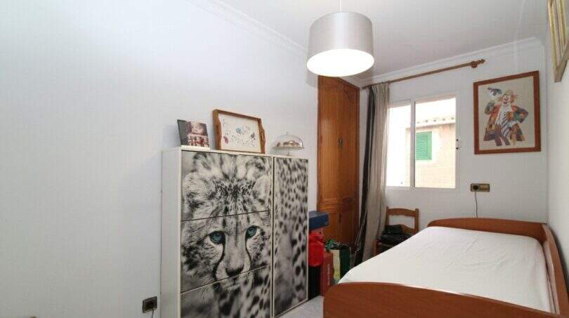 Kleines Schlafzimmer im Stadthaus Portixol mit Einzelbett, Kommode mit Leoparden-Motiv und Wanddeko.
