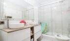 Helles Badezimmer im Stadthaus Portixol mit Doppelwaschbecken, Glasdusche und modernen weißen Möbeln.