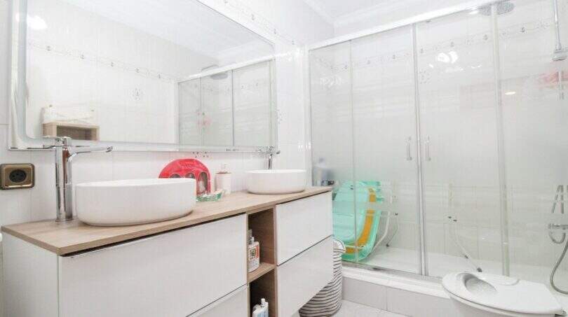 Helles Badezimmer im Stadthaus Portixol mit Doppelwaschbecken, Glasdusche und modernen weißen Möbeln.
